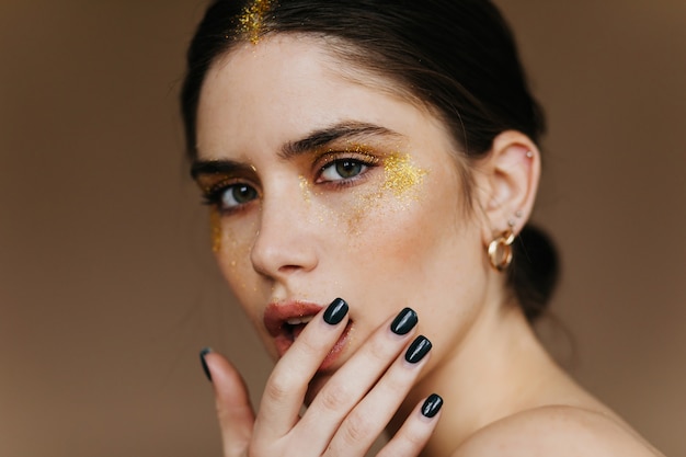 Spectacular black-haired woman  with interest. Close-up shot of stunning brunette girl with party makeup.