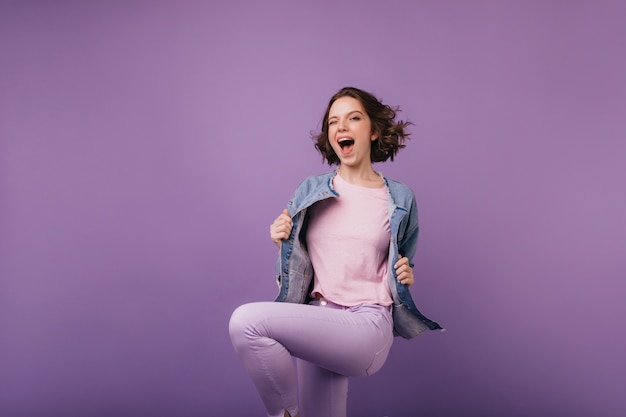 Spectacular slim girl in purple pants jumping with smile. Appealing female model expressing happiness.