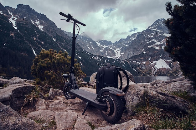 Spectacular view of mountains, pines and low gloomy clouds with backpack and scooter at the front.
