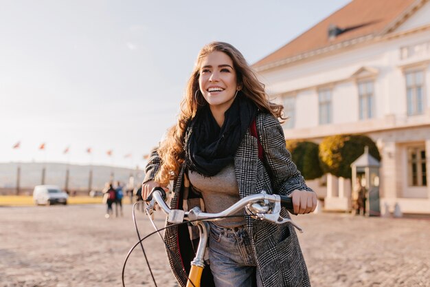 Spectacular woman with black scarf posing with happy face expression near big house