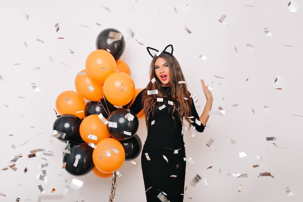 Free photo spectacular woman with long hair standing under confetti with surprised smile
