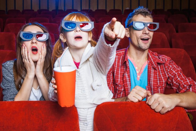 Зрители сидят в кинотеатре и смотрят кино с чашками колы.