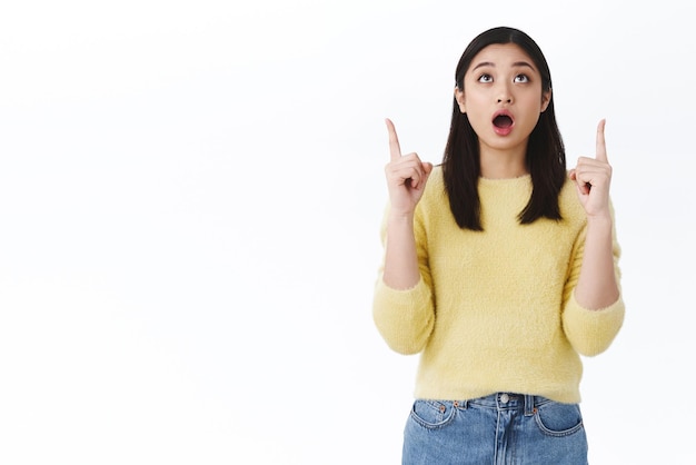 Free photo speechless amazed beautiful vietnamese girl open mouth from show saying wow as looking pointing up staring startled in awe at awesome promo discount offer standing over white background