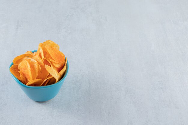 Spiced crispy chips in blue bowl on stone.