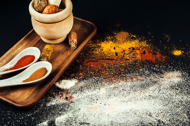 Spices composition with mill and spoons on board
