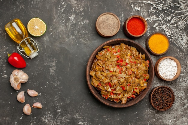 spices and dish garlic red bell pepper bottle of oil next to the plate of green beans and four bowls of spices