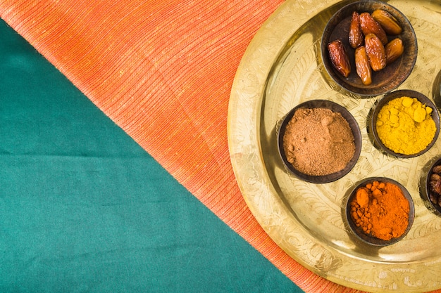 Spices and dry fruits on tray on textile