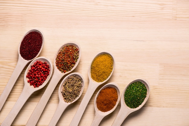 Free photo spices in spoons on wooden table