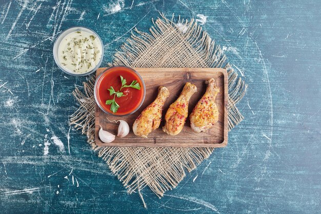 Spicy chicken meat on a wooden board with sauces.