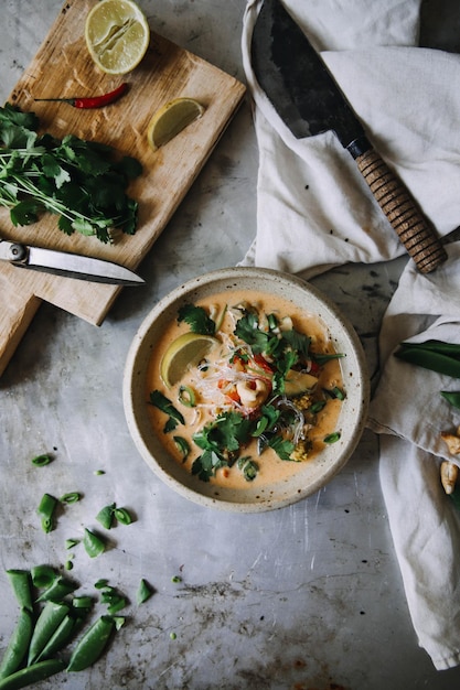 Spicy cream soup decorated with lemon and parsley on a gray table