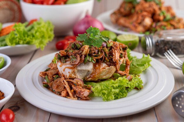 Spicy minced chicken on a white plate complete with cucumber, lettuce and side dishes.