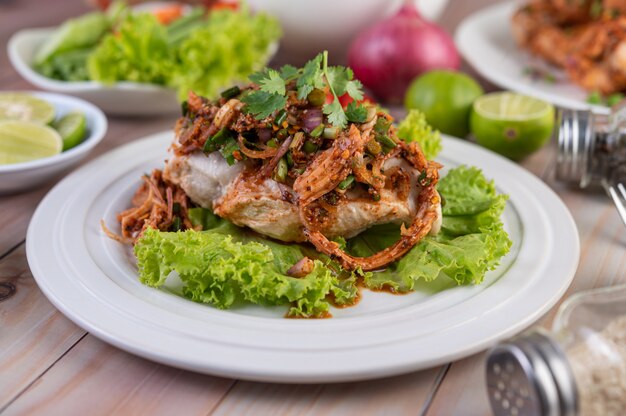 Spicy minced chicken on a white plate complete with cucumber, lettuce and side dishes.