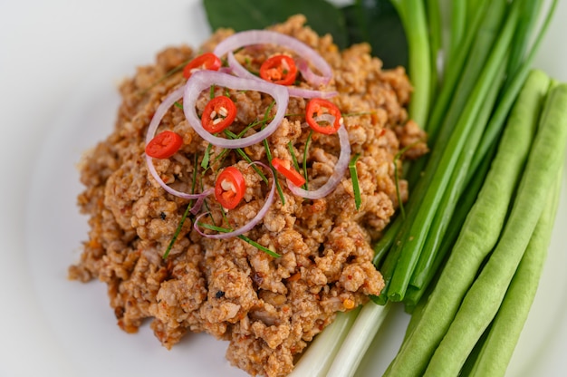 Free photo spicy minced pork salad on a white plate with lentils, kaffir lime leaves and spring onions.