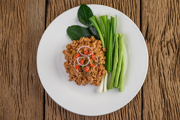 Spicy Minced Pork Salad on a white plate with lentils, kaffir lime leaves and spring onions.