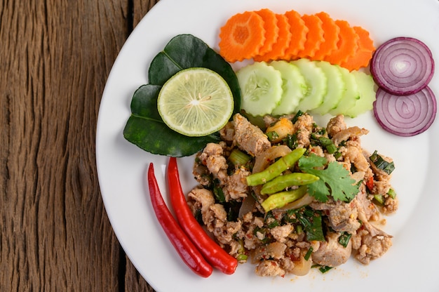 Spicy Minced Pork Salad on a white plate on wooden table.