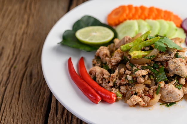 Spicy Minced Pork Salad on a white plate on wooden table.