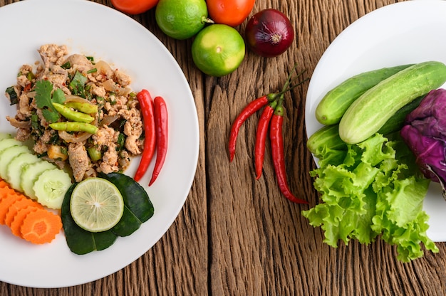 Spicy Minced Pork Salad on a white plate on wooden table.