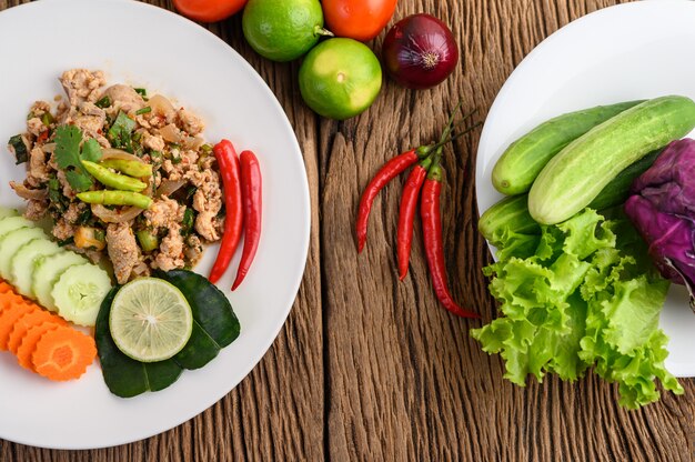 Spicy Minced Pork Salad on a white plate on wooden table.