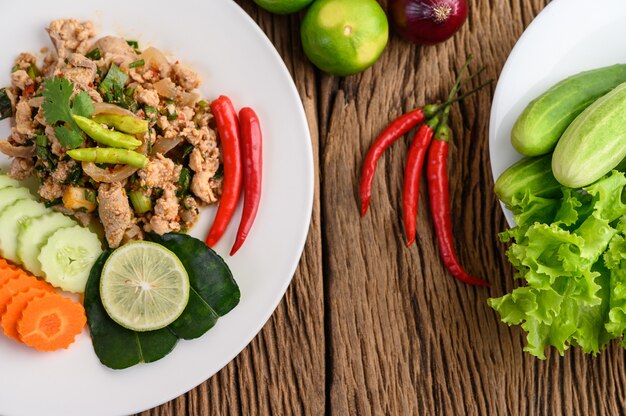 Spicy Minced Pork Salad on a white plate on wooden table.