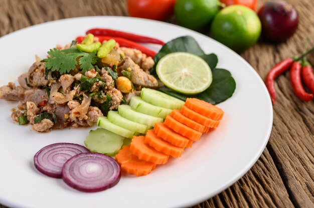 Spicy Minced Pork Salad on a white plate on wooden table.