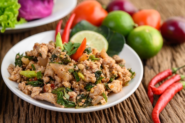 Spicy Minced Pork Salad on a white plate on wooden table.