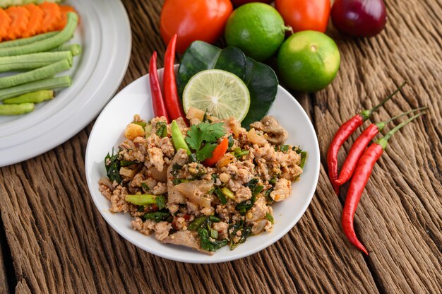 Spicy Minced Pork Salad on a white plate on wooden table.