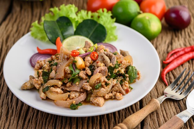 Spicy Minced Pork Salad on a white plate on wooden table.