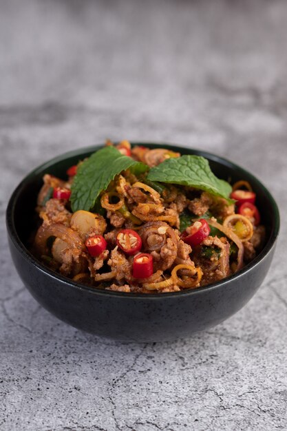 Spicy pork chops in a black cup consisting of lemons and chilies