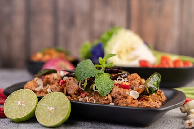 Spicy pork chops on a black plate consisting of lemons Chili and side dishes