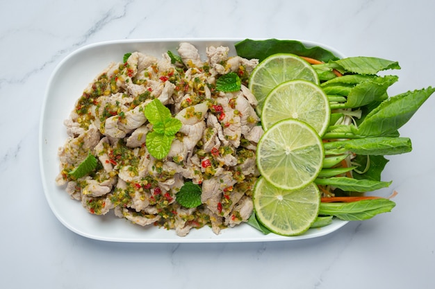 Insalata di maiale piccante servita con gambi di cavolo fresco croccante cibo tailandese.