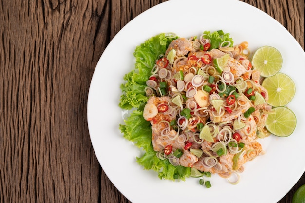 Spicy pork salad with galangal, lemon, chilli, garlic and put in a salad on a white plate.