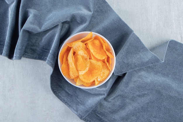 Spicy potato chips and blue cloth on stone.