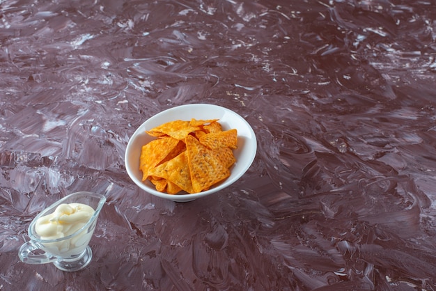 Patatine piccanti in una ciotola e yogurt in un bicchiere, sul tavolo di marmo.