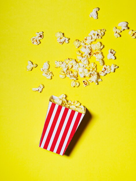 Spilled box of popcorn on yellow background