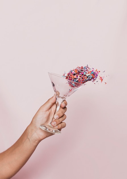 Free photo spilling confetti out of transparent glass at new years party