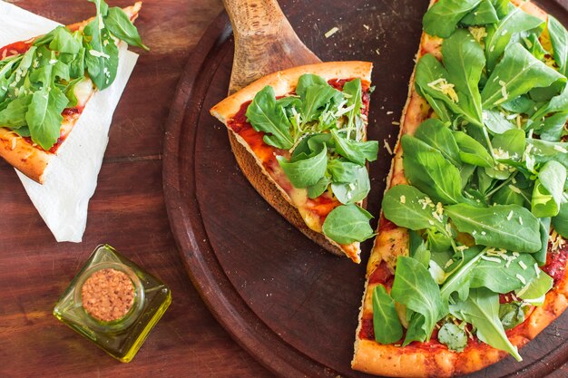 Spinach on pizza slice over wooden circular tray