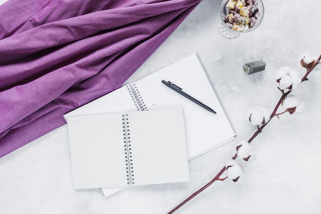 Spiral notebook with pen near the raw cotton twig