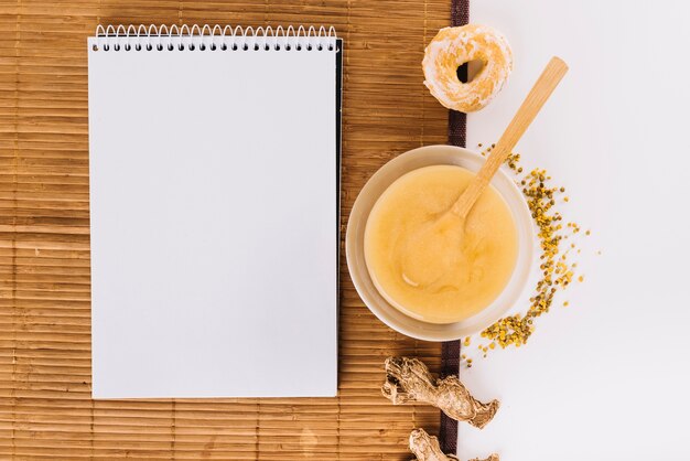 Spiral notepad; lemon curd; bee pollen; donut and ginger on placemat