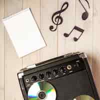 Бесплатное фото Спиральный блокнот; музыкальное примечание и усилитель с компакт-диском на деревянном столе