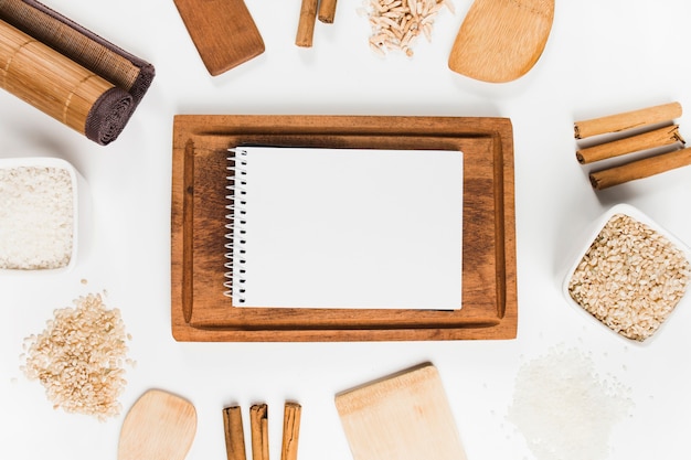 Spiral notepad on wooden tray surrounded with rice and cinnamon sticks