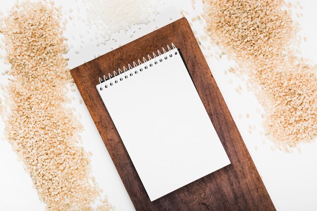 白い背景に米の様々な木製トレイにスパイラルメモ帳
