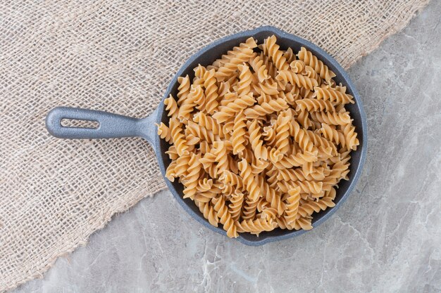 Spiral pastas in an iron pan on the marble