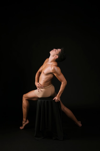 Free photo spiritual man stretching by body sitting on chair