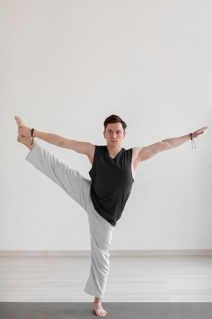 Духовный молодой человек, практикующий йогу в помещении