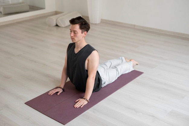 Spiritual young man practicing yoga indoors