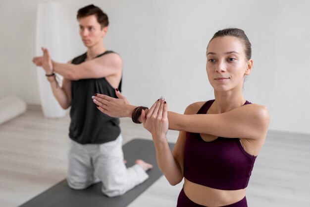 Духовный молодой мужчина и женщина, практикующие йогу в помещении