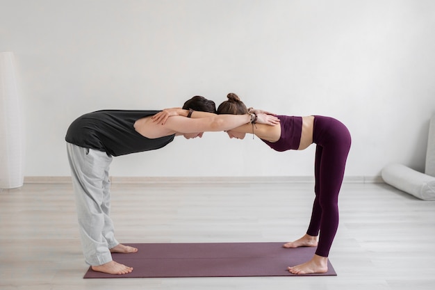 Spiritual young man and woman practicing yoga indoors