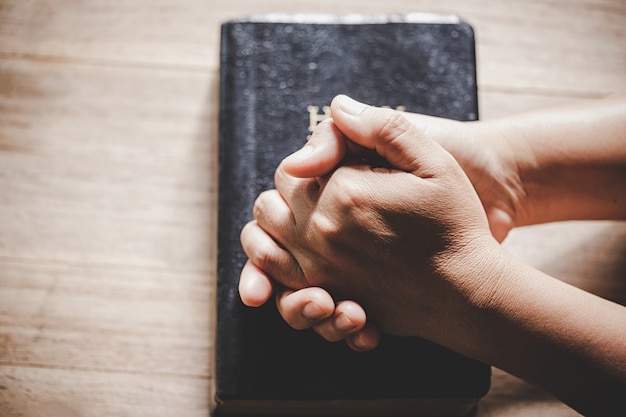 Spirituality and religion, Hands folded in prayer on a Holy Bible in church concept for faith.