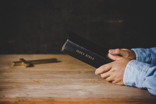 Spirituality and religion, Hands folded in prayer on a Holy Bible in church concept for faith.