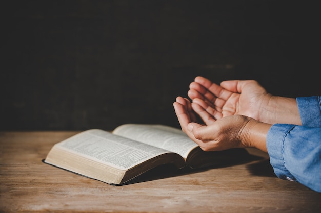 spirituality and religion, hands folded in prayer on a holy bible in church concept for faith.